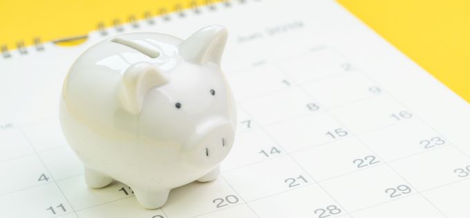White-Piggy-Bank-Standing-on-a-Calendar-680x315px
