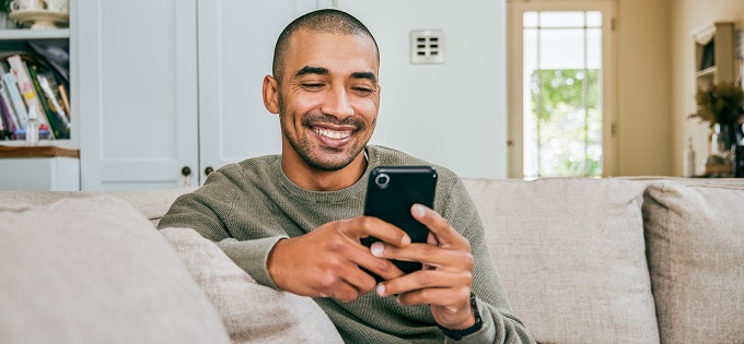 Young-Man-Smiling-at-Smartphone-680x315