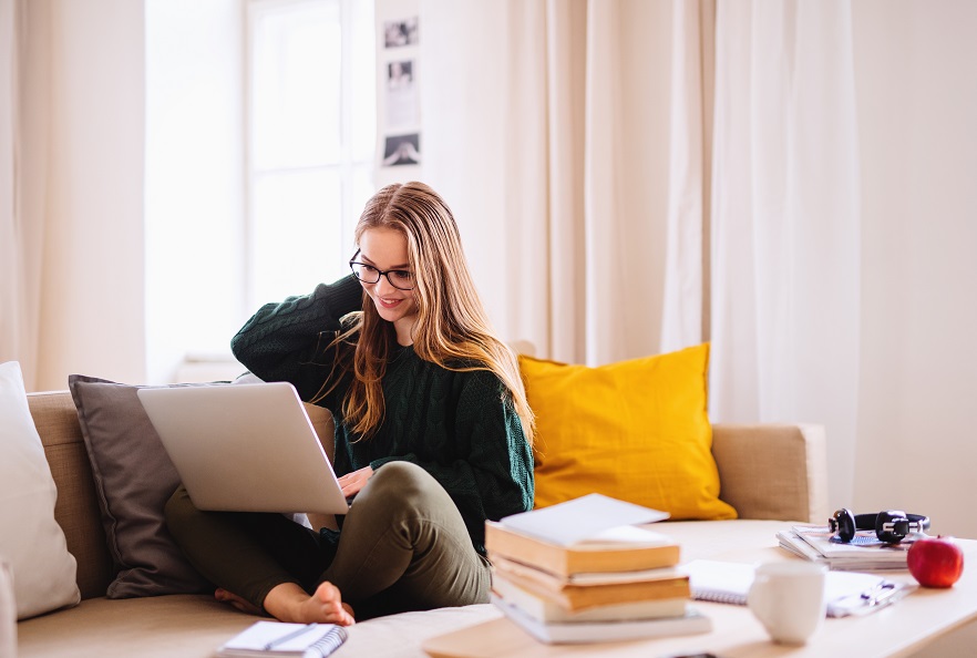 Young Woman Studies Laptop on Sofa